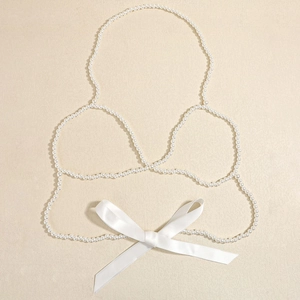 Catena per il corpo sexy con perle stile bikini e fiocco in raso bianco su sfondo beige
