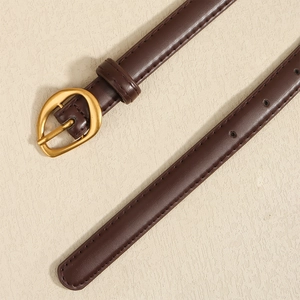 Close-up of dark brown slim belt featuring a gold oval buckle and fine stitching details