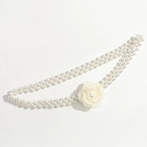 Detail of white double-row pearl waist chain featuring a delicate camellia flower ornament