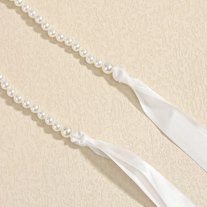 Dettaglio catena corpo con perle bianche e chiusura in elegante nastro di raso
