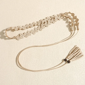 Dettaglio cintura a fiori tagliata al laser con perle di legno e nappe marroni