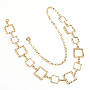 Detail of golden metal waist chain featuring textured square hollow links and lobster clasp