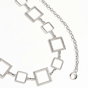 Macro detail of geometric silver metal waist chain with square links and engraved texture