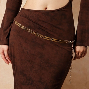 Dettaglio della catena dorata in vita con maglie rettangolari lucide su vestito marrone