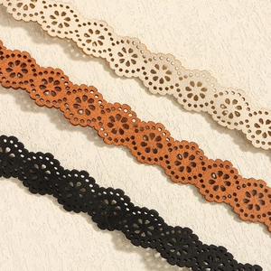 Dettaglio dei motivi a girasole tagliati al laser su cinture in vita nei colori beige e nero