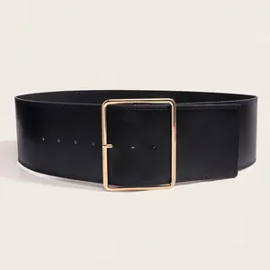 Détail d'une large ceinture en cuir noir montrant les coutures et une boucle dorée
