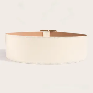 Détail d'une large ceinture en cuir crème avec double surpiqûre et boucle en métal doré