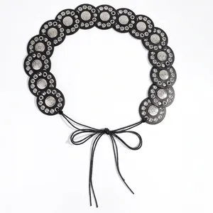 Detail view of retro ethnic wide belt with circular patches and silver embossed metal floral motifs
