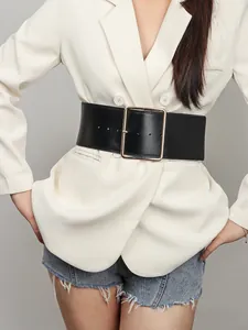 Détail d'une large ceinture noire en cuir avec une grande boucle carrée en métal doré