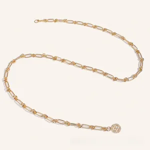 Gros plan sur la ceinture chaîne en métal doré avec pendentif rond orné de strass