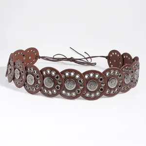 Detail of bohemian waist belt featuring circular brown leather with silver embossed metal