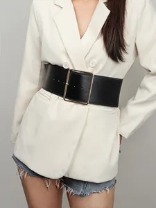 Vue détaillée d'une large ceinture noire avec boucle dorée carrée sur une veste de blazer