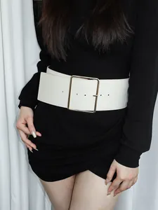 Détail d'une large ceinture blanche avec boucle dorée portée sur une robe noire
