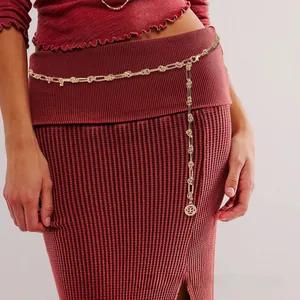 Détail de la chaîne de taille dorée avec pendentif logo rond sur robe rouge