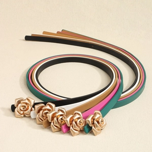 Detail of five slim faux leather belts with golden rose buckles in various colors