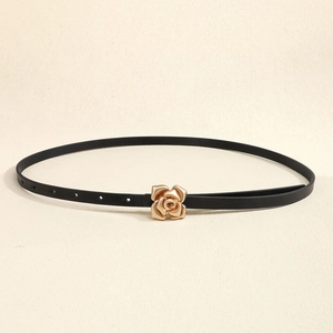 Detail of elegant gold rose buckle on a slim black leather belt for women