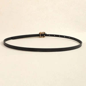 Detail of slim black waist belt featuring a textured gold-tone rose embossed metal buckle