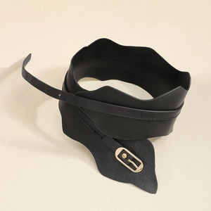 Détail d'une large ceinture noire avec bords ondulés et boucle dorée claire sur fond beige