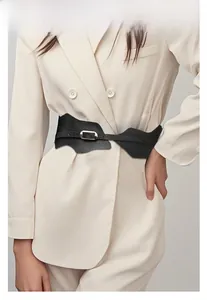 Détail de la ceinture corset noire à bords ondulés et boucle dorée sur un blazer