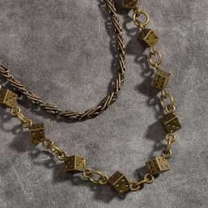 Vue macro de chaînes vintage superposées avec pendentifs dés de style industriel chic