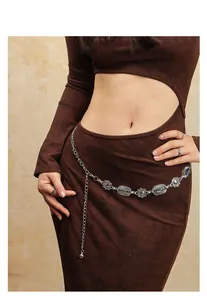 Gros plan d'une chaîne de taille bohème vintage en métal sur une robe ajourée marron