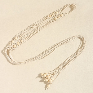 Détail d'une ceinture bohème en corde tressée avec perles en bois et pompons à franges