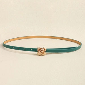 Detailed macro view of green slim belt with a gold rose-shaped buckle on beige background