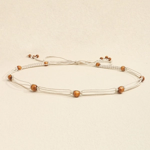 Detail of bohemian hand-woven waist chain with natural wooden beads and cream tassels