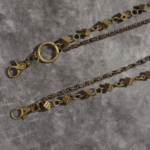 Détail d'une chaîne de pantalon vintage en bronze avec dés et mousquetons à ressort