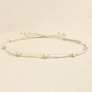 Close-up of bohemian hand-woven cream waist rope with decorative round beads for dresses