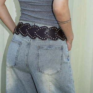Détail de la ceinture en cuir marron foncé avec bords en cœur et rivets argentés