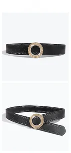 Détail d'une ceinture large noire à points évidés avec boucle ronde à strass brillants