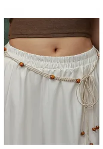 Macro detail of bohemian hand-woven waist chain with wooden beads and tassel