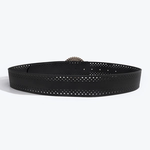 Détail de la ceinture noire en cuir avec motifs ajourés et boucle métallique texturée