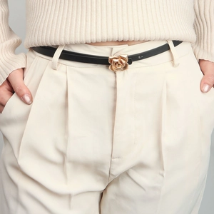 Close-up of a golden rose flower buckle on a minimalist black leather belt for women