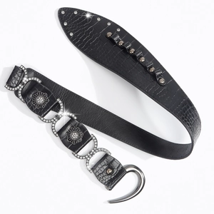 Close-up of black crocodile pattern belt with rhinestone floral studs and metal rivets