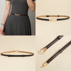Detail view of a slim dark brown leather belt with a golden heart-shaped metal buckle