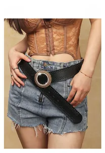 Détail de ceinture large noire avec boucle ronde en strass sur un short en jean