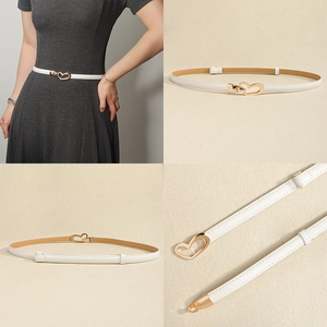 Close-up of white leather belt with gold heart-shaped metal buckle on a grey dress