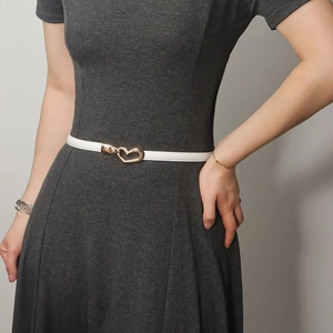 Close-up of white slim leather belt with gold heart buckle on grey dress