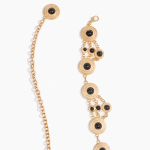 Macro detail of Bohemian waist chain featuring black beads on gold textured metal base