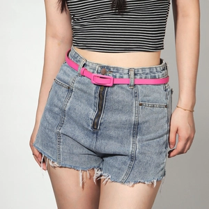 Ceinture fine rose fluo avec boucle rectangulaire sur un short en jean bleu
