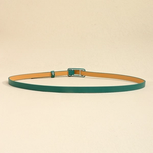 Détail d'une ceinture fine en cuir vert foncé avec boucle en métal sur fond beige