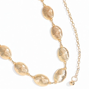 Macro detail of golden oval metal link chain belt with textured surface and beads