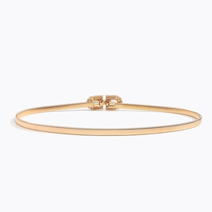 Détail macro d'une ceinture métallique dorée élastique avec boucle strass géométrique