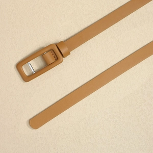 Détail d'une ceinture fine en cuir caramel avec boucle rectangulaire gainée de cuir