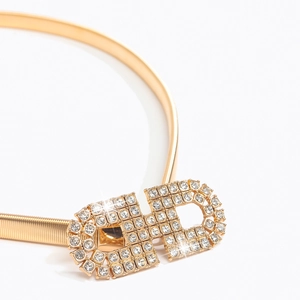 Vue détaillée de la ceinture élastique dorée avec boucle double carrée ornée de strass