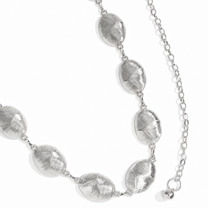 Close-up of silver oval link waist chain with radial brushed texture and bead charm
