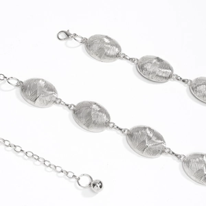 Macro shot of silver oval metal chain link belt with textured surface and lobster clasp