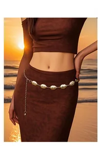 Close-up of golden oval chain belt with textured links on a long dress at sunset